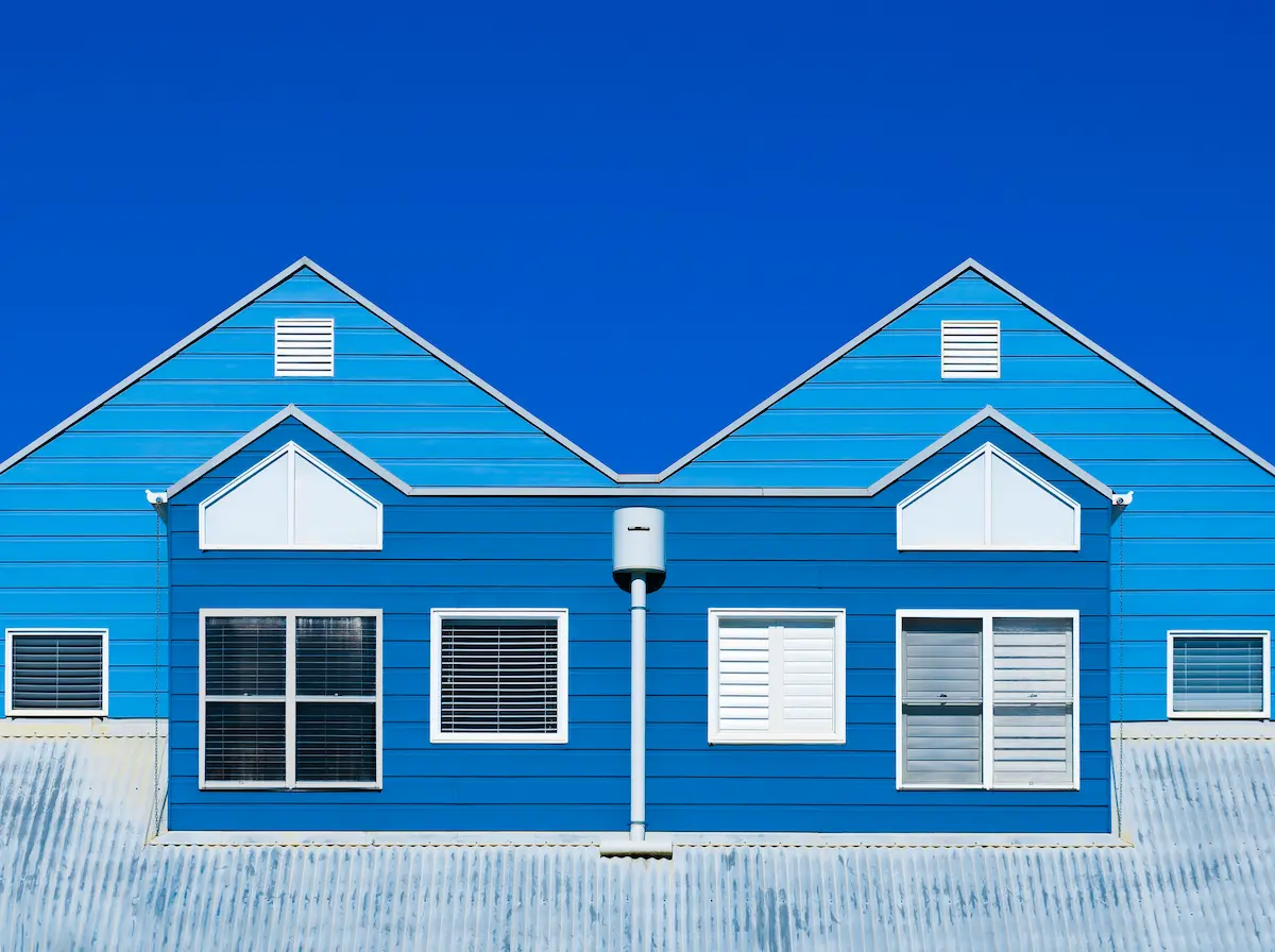 Line-art illustration of a row of apartment buildings with lit windows at dusk